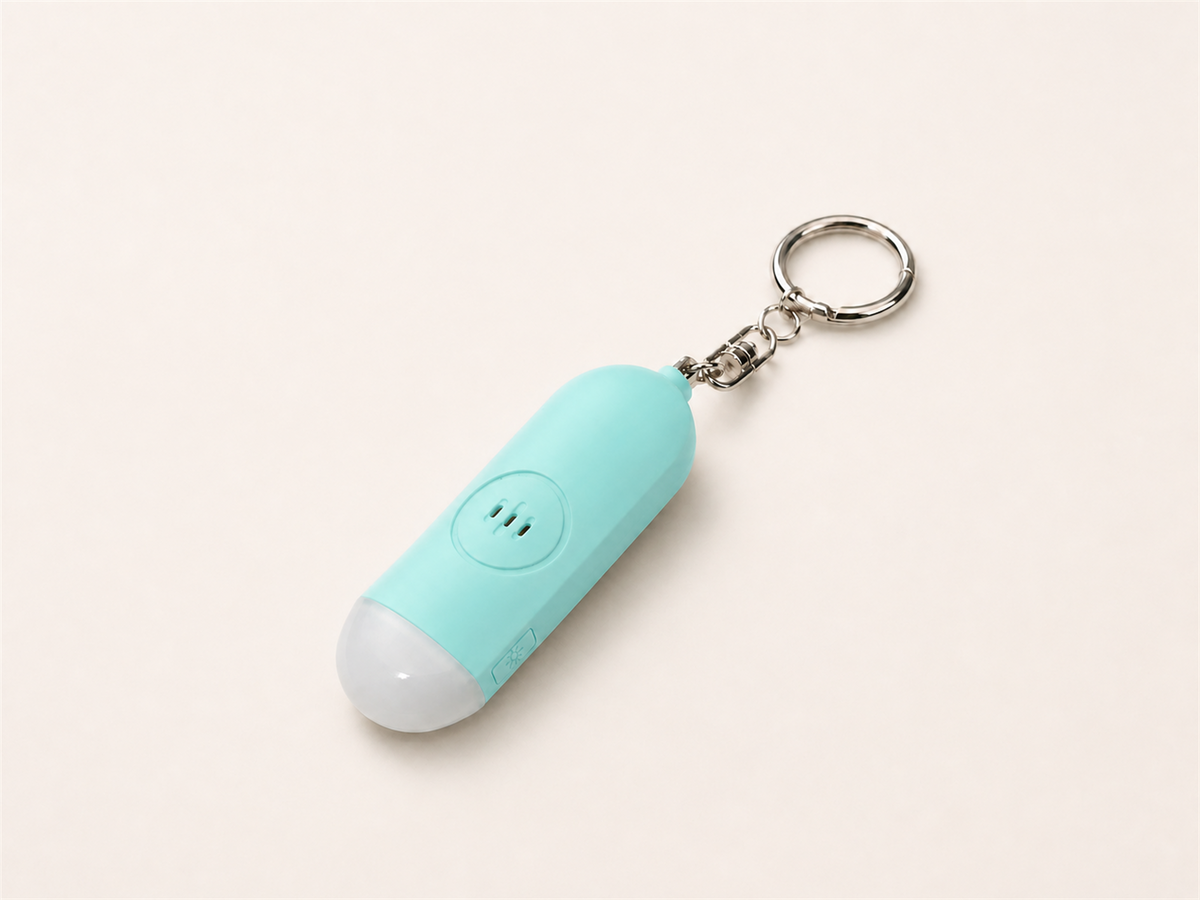 Mint Lumae personal safety alarm, back view with three-slot speaker and silver keychain
