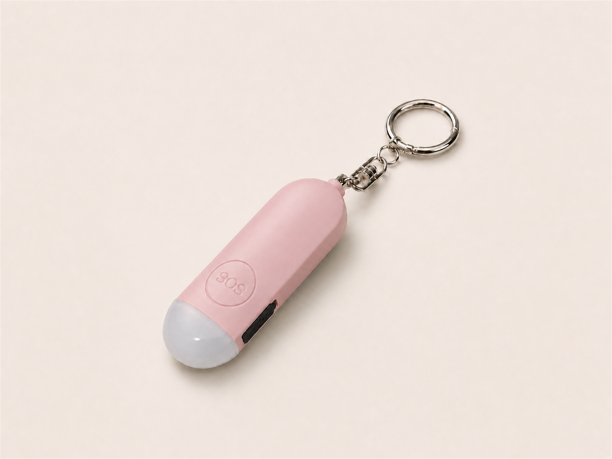 Pink Lumae personal safety alarm, front view with round SOS button and silver keychain