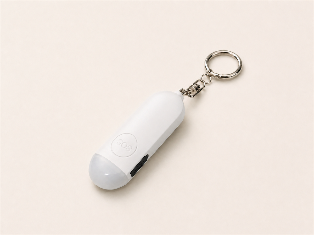 White Lumae personal safety alarm, front view with round SOS button and silver keychain